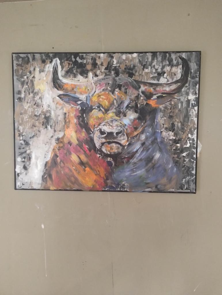 Schilderij van een kleurrijke stier, met abstracte achtergronden in levendige tinten, op een canvasdoek.